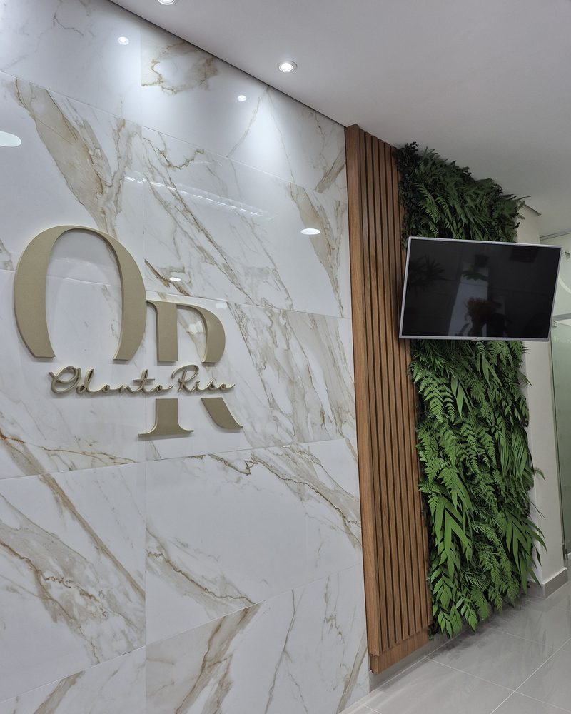 Nicho de jardim vertical artificial com TV integrada na clínica Odonto Riso